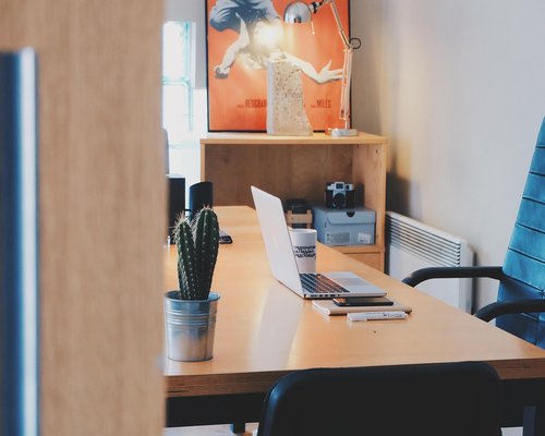 Modern comfortable desk area with laptop open and natural light streaming in