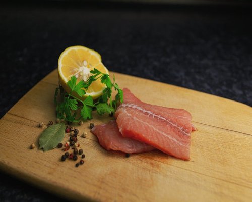 Fresh raw fish fillet seasoned with lime slices and spices ready for cooking