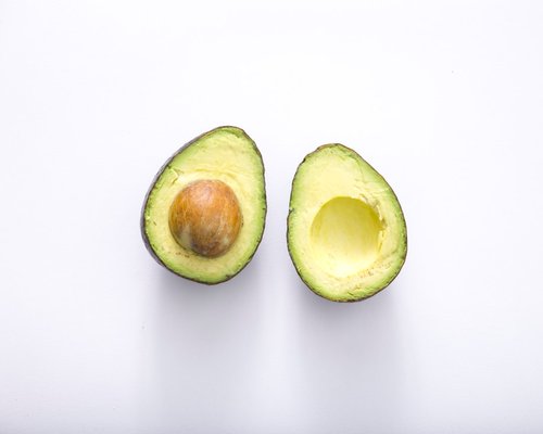 Ripe avocado cut in half showing the textured pit and smooth green pulp